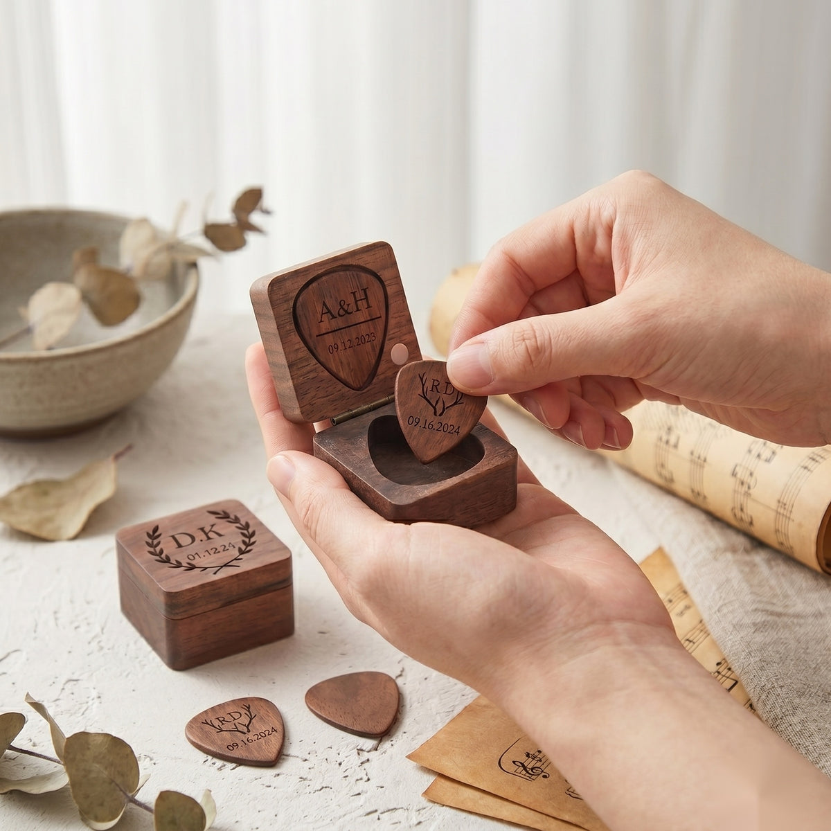 Hands opening a personalized walnut guitar pick box with engraved picks